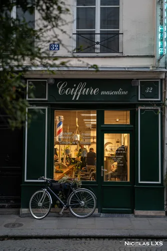 Devanture vert sombre d'un salon de coiffure, vélo garé devant