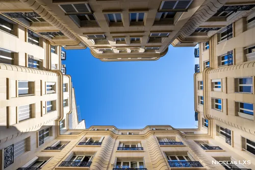 Ciel bleu encadré par les façades d'une cour d'immeuble, en contre-plongée